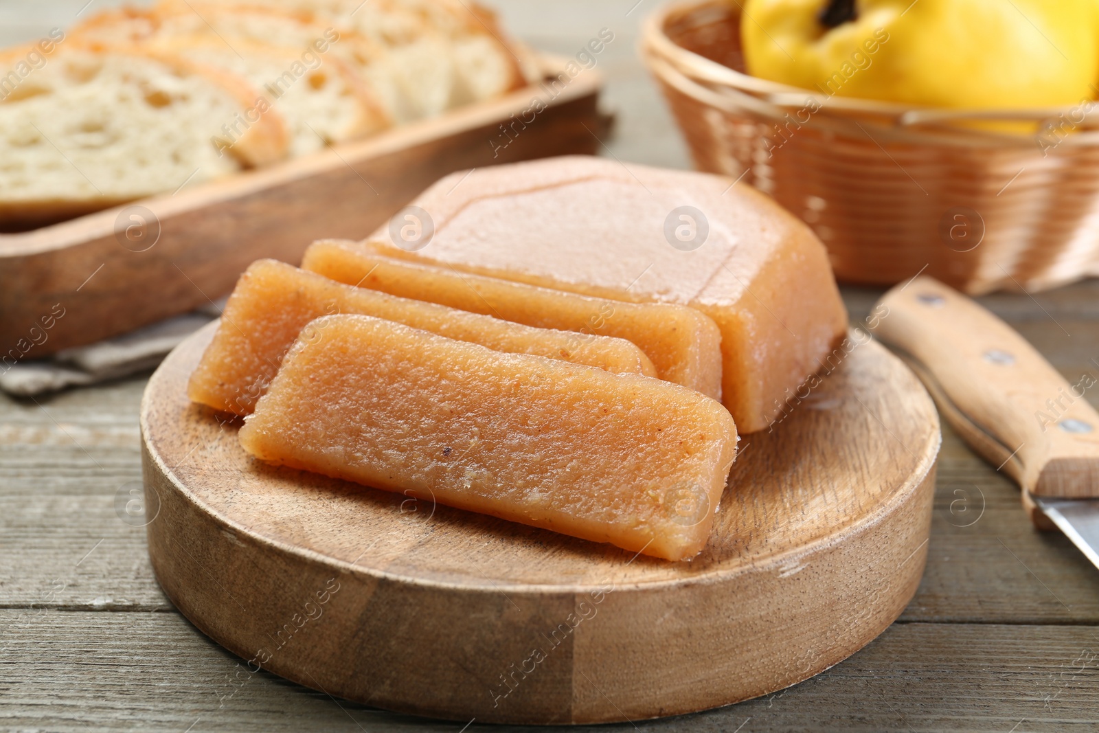 Photo of Tasty sweet quince paste, fresh fruit, bread and knife on wooden table, closeup
