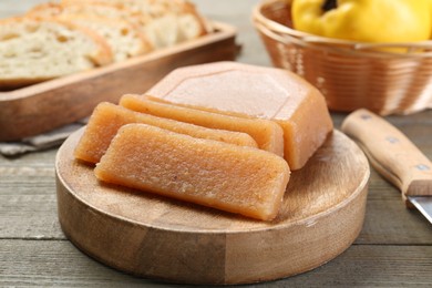 Tasty sweet quince paste, fresh fruit, bread and knife on wooden table, closeup
