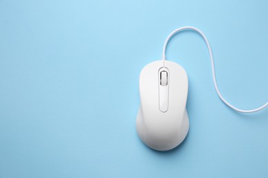 Photo of One wired mouse on light blue background, top view. Space for text