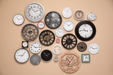 Collection of stylish clocks on beige wall