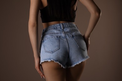 Photo of Slim woman with smooth skin in denim shorts on beige background, closeup. Cellulite problem concept