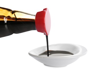 Photo of Pouring soy sauce into bowl against white background