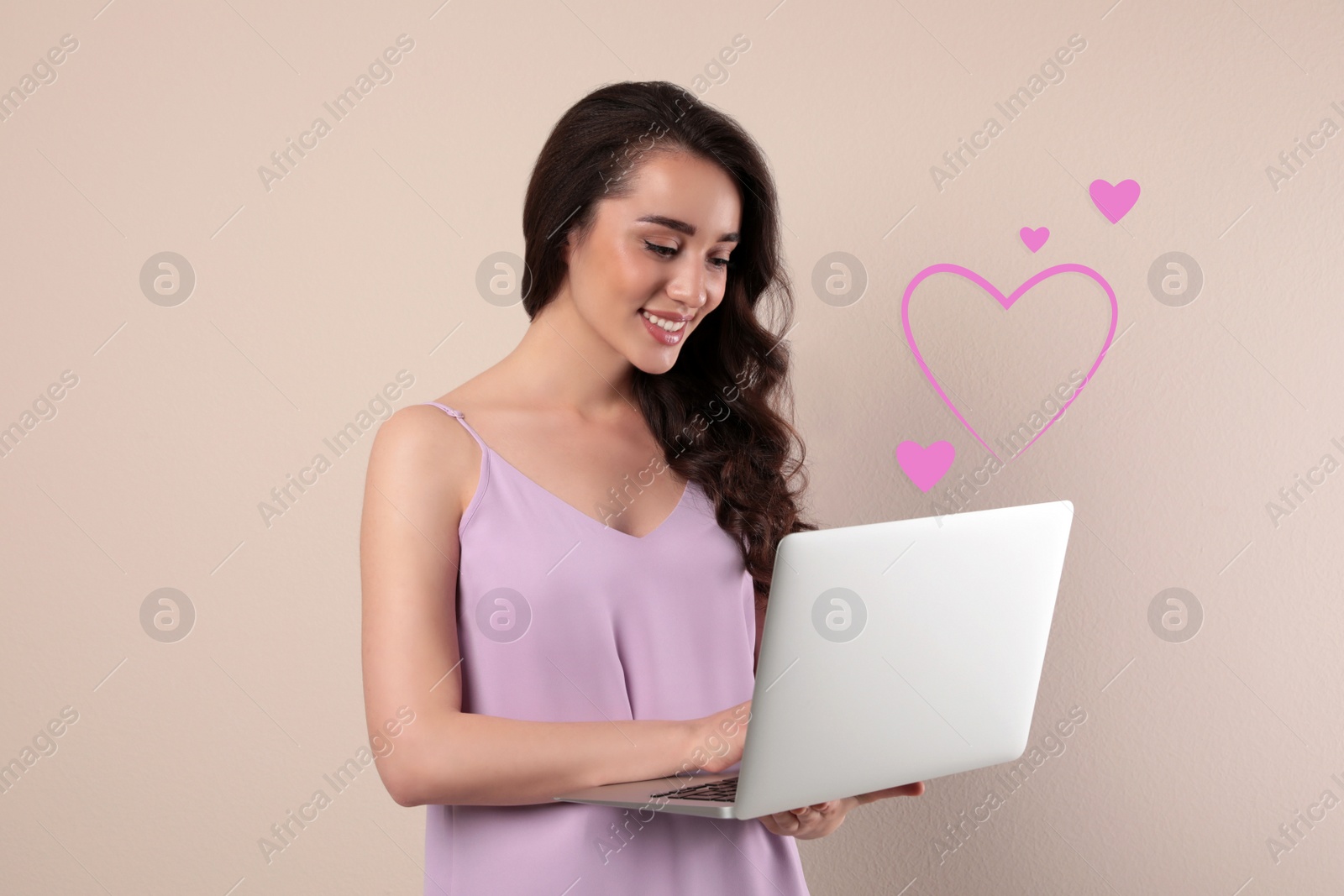 Image of Young woman visiting dating site via laptop on beige background