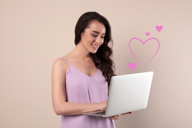 Image of Young woman visiting dating site via laptop on beige background