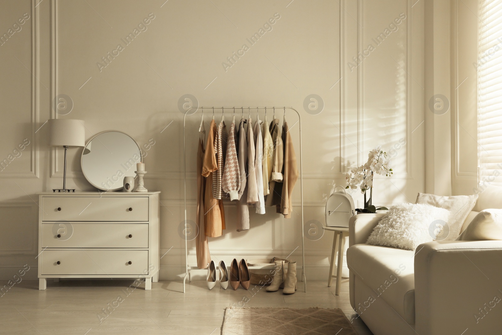Photo of Modern dressing room interior with stylish clothes, shoes and beautiful orchid flowers