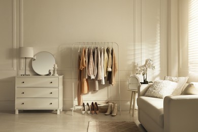 Modern dressing room interior with stylish clothes, shoes and beautiful orchid flowers