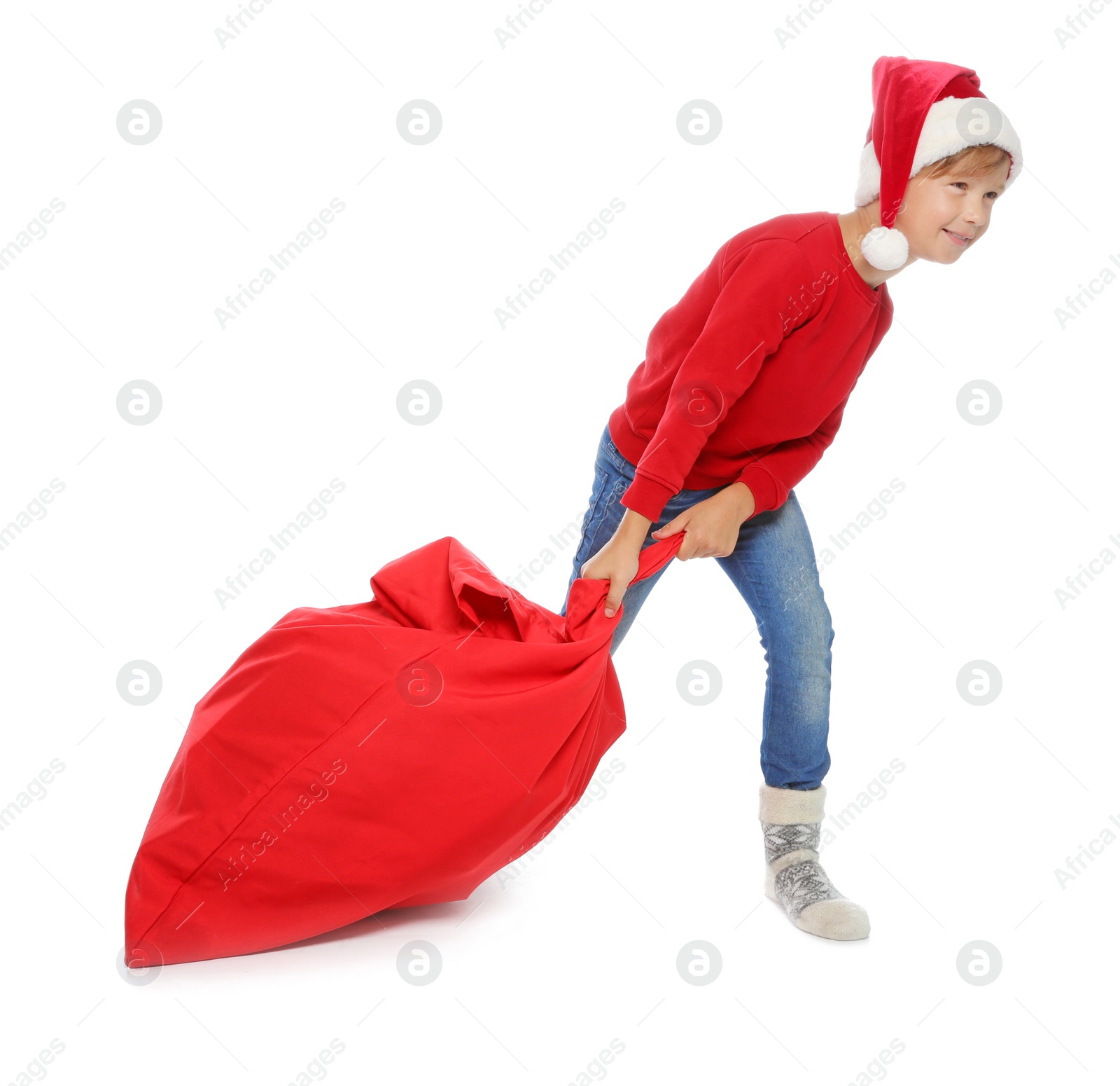 Photo of Cute little child in Santa hat with red Christmas bag on white background