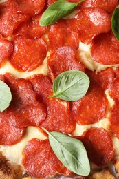 Photo of Tasty pepperoni pizza with basil as background, top view