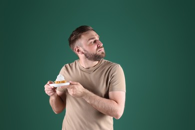 Photo of Greedy young man hiding cupcake on green background