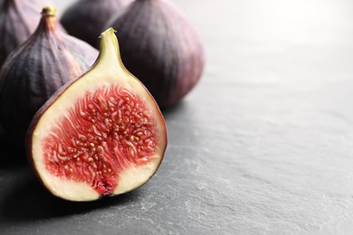 Whole and cut fresh figs on grey table, closeup. Space for text