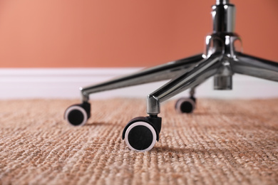 Photo of Modern office chair with wheels on floor, closeup