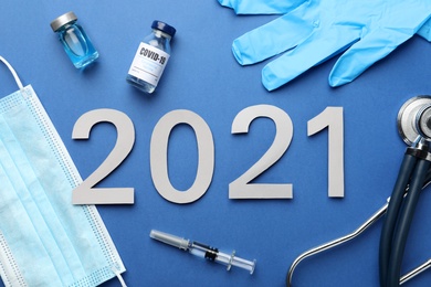 Photo of Flat lay composition with coronavirus vaccine and number 2021 on blue background