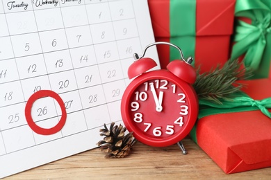 Photo of Calendar with marked Boxing Day date, alarm clock and gifts on wooden table