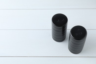 Salt and pepper shakers on white wooden table, above view. Space for text
