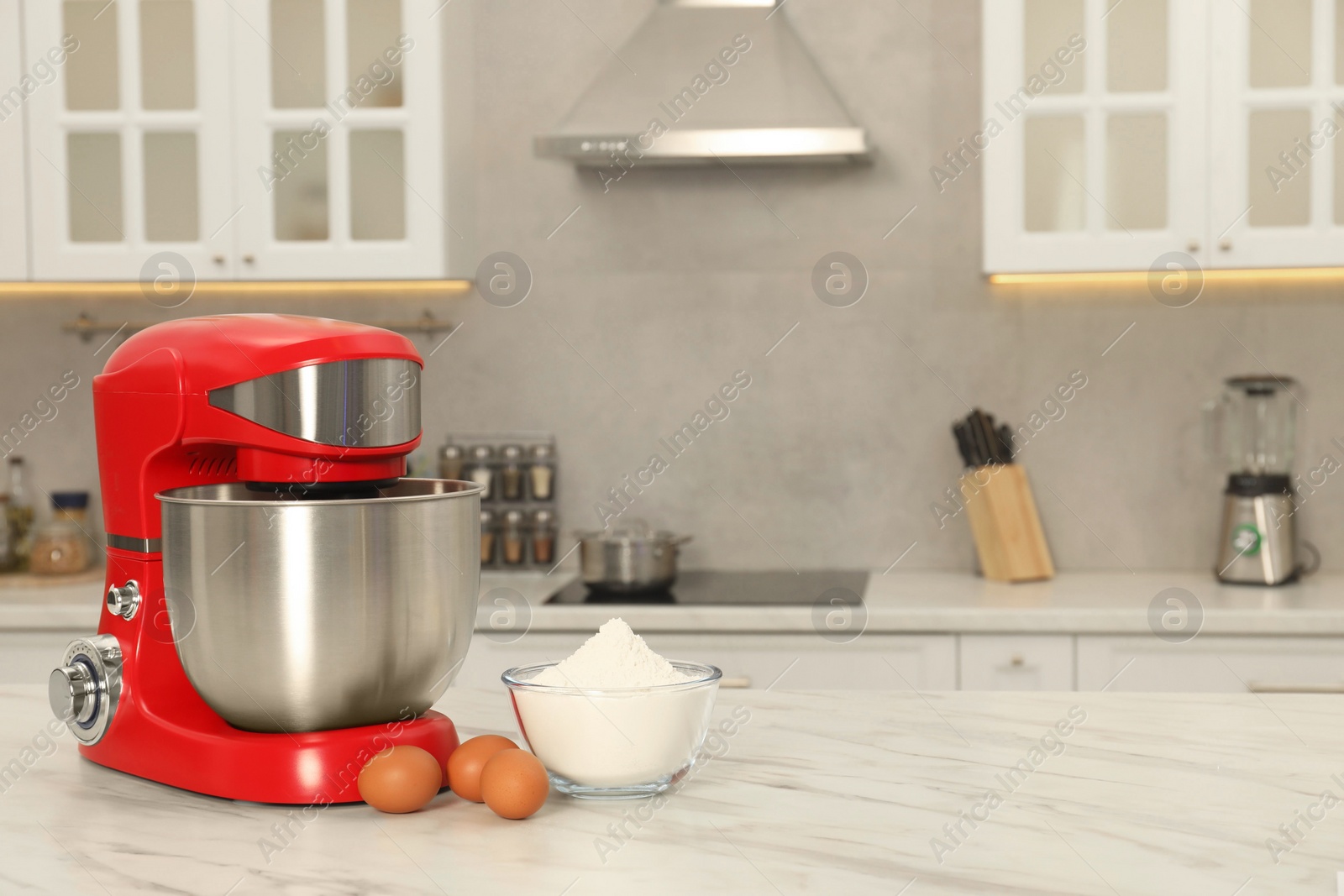 Photo of Modern red stand mixer, eggs and bowl with flour on white marble table in kitchen, space for text