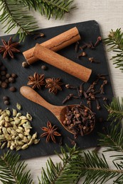 Photo of Different spices and fir branches on wooden table, flat lay
