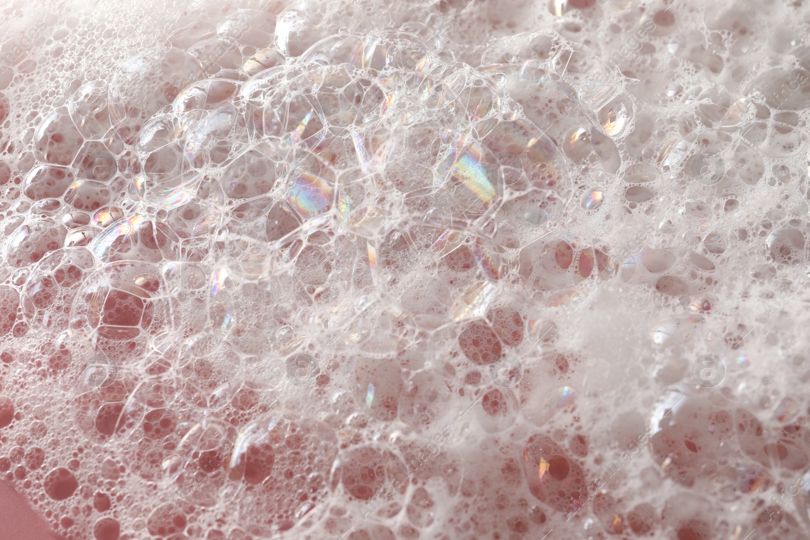 Photo of White washing foam on pale pink background, closeup