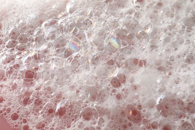 Photo of White washing foam on pale pink background, closeup