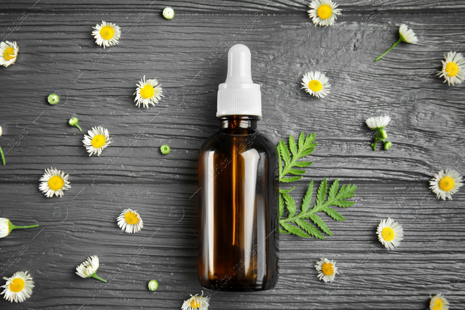 Photo of Flat lay composition with essential oil and flowers on wooden background