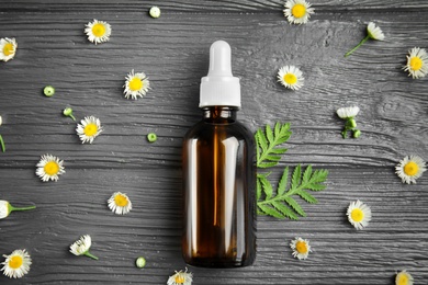 Flat lay composition with essential oil and flowers on wooden background