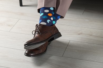 Photo of Man wearing stylish shoes and colorful socks indoors, closeup