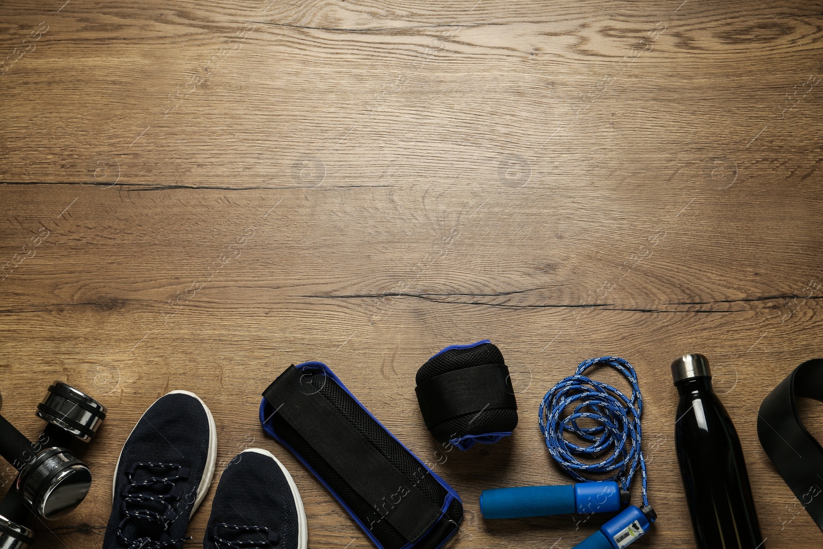 Photo of Blue weighting agents and sport equipment on wooden table, flat lay. Space for text