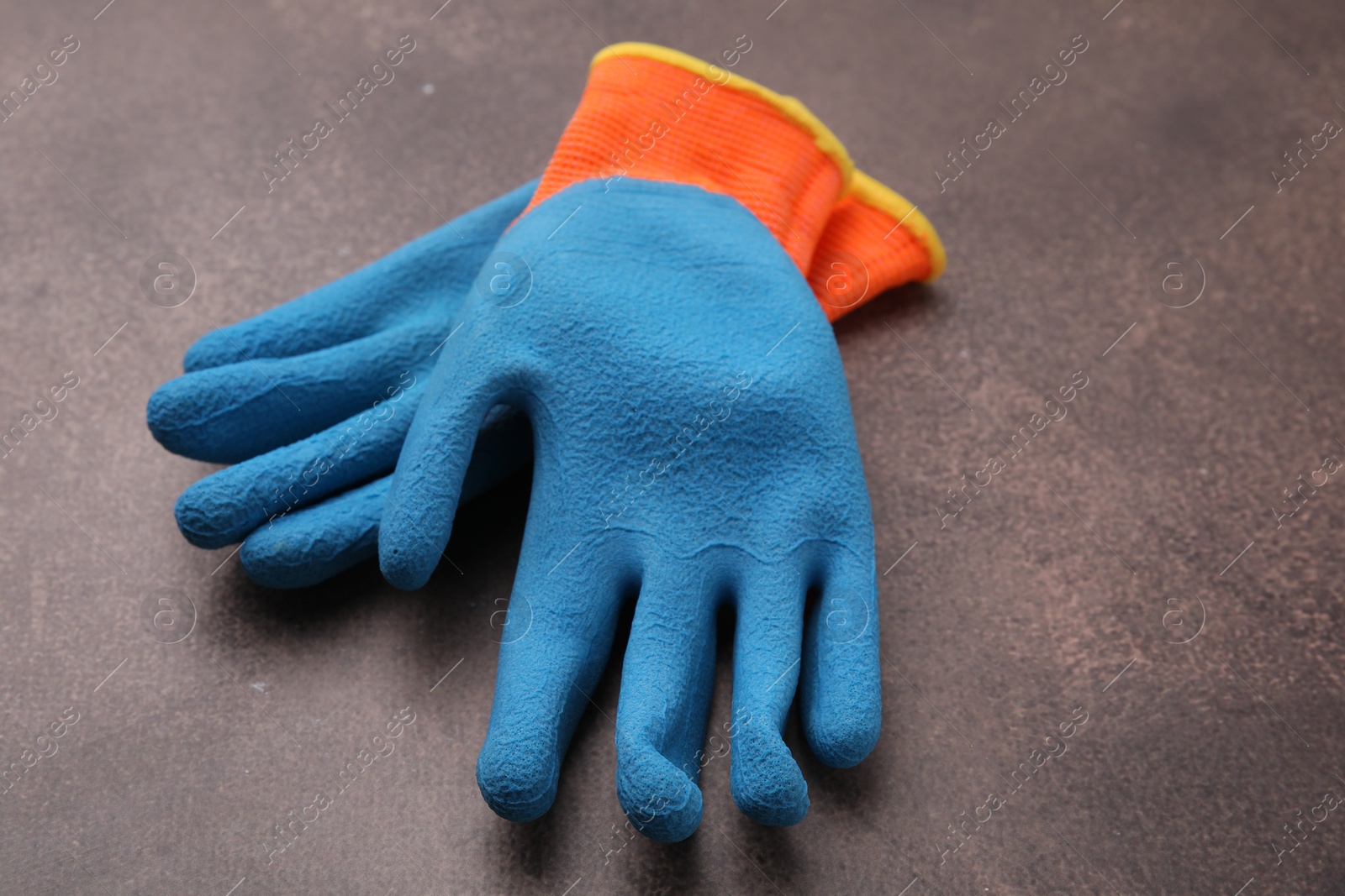 Photo of Pair of color gardening gloves on brown textured table