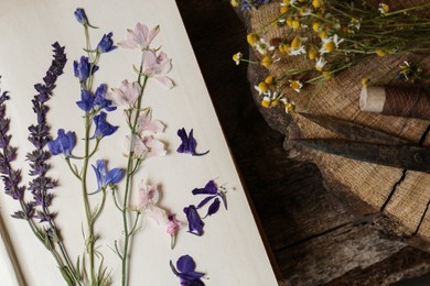 Composition with beautiful dried flowers and book on wooden table, top view