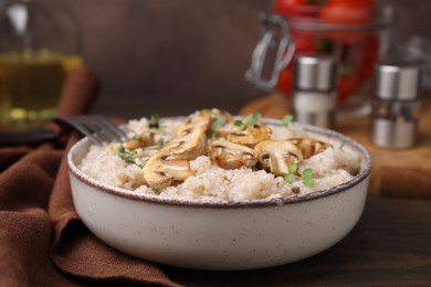 Photo of Delicious barley porridge with mushrooms and microgreens in bowl on table, closeup