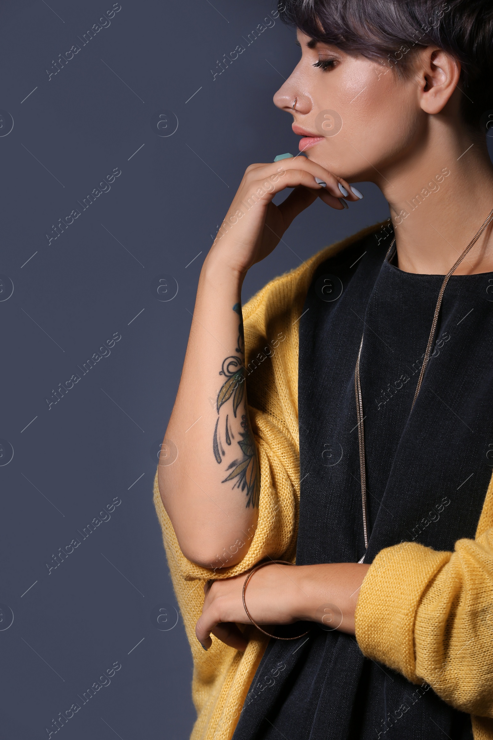 Photo of Trendy young woman with tattoo on grey background