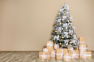 Photo of Blurred view of decorated Christmas tree and gift boxes near beige wall. Space for text