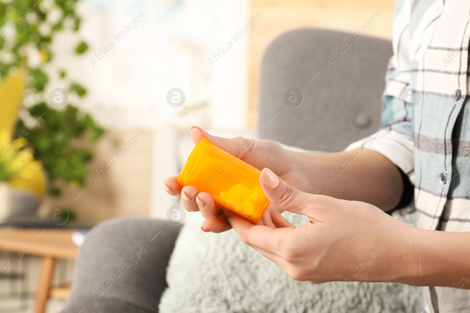 Photo of Woman holding bottle of pills indoors, closeup view