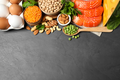 Photo of Different products rich in protein on black table, above view. Space for text