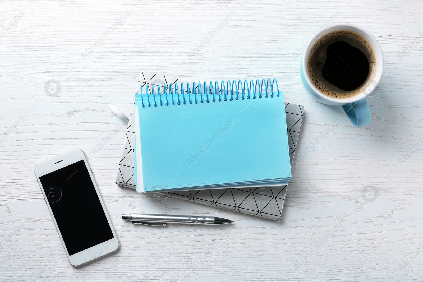 Photo of Flat lay composition with stationery, cup of coffee and smartphone on white wooden background. Space for text