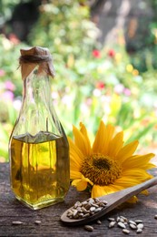 Photo of Bottle of sunflower oil and peeled seeds on wooden table outdoors