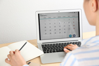 Woman using calendar app on laptop in office, closeup