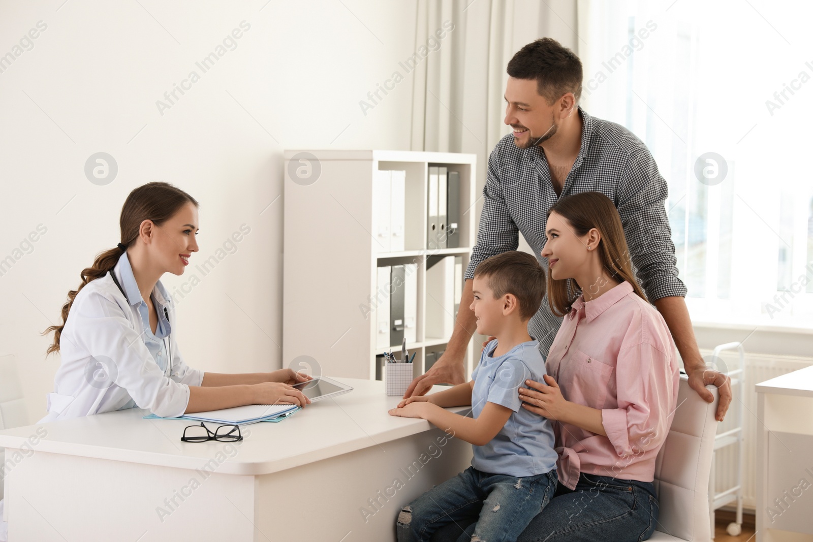 Photo of Parents and son visiting pediatrician. Doctor working with patient in hospital