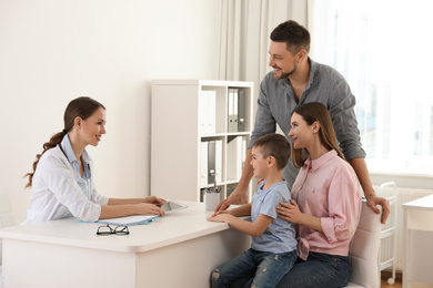 Photo of Parents and son visiting pediatrician. Doctor working with patient in hospital