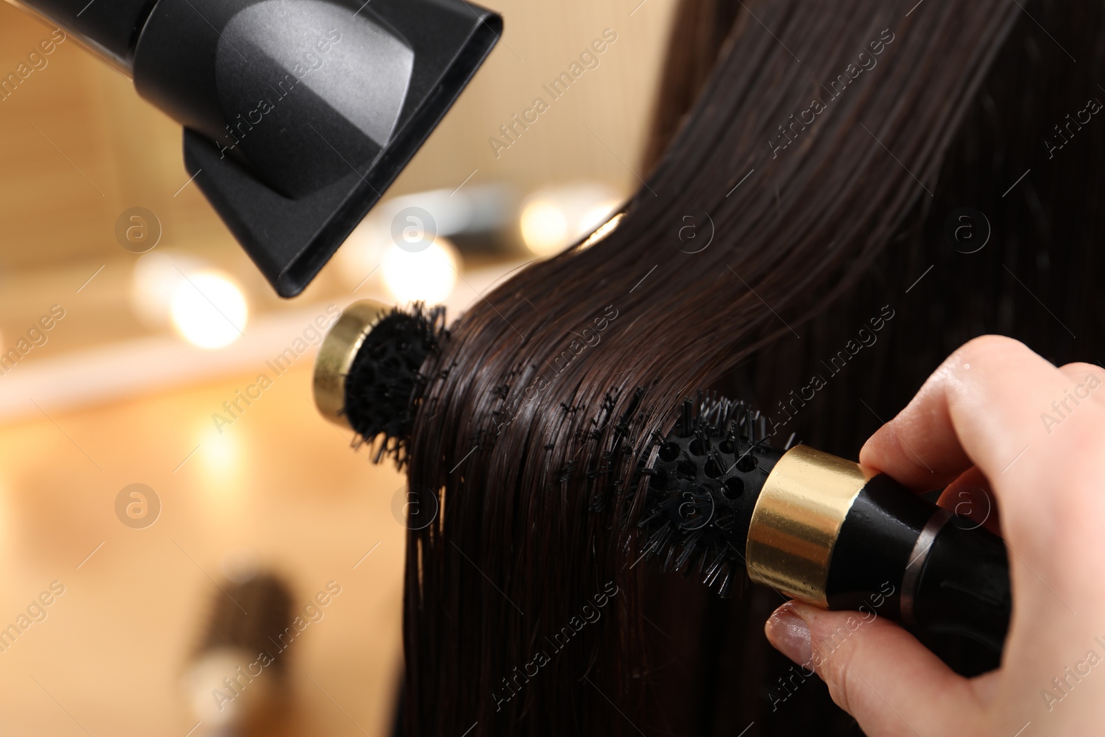 Photo of Hairdresser blow drying client's hair in salon, closeup