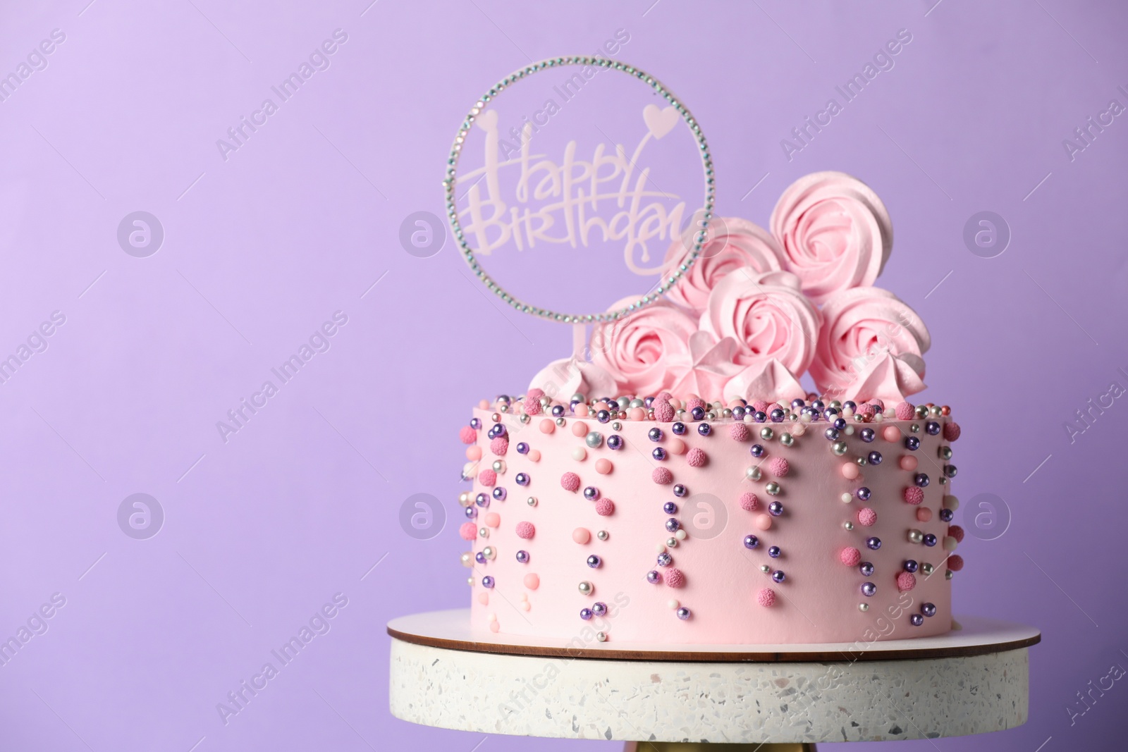 Photo of Beautifully decorated birthday cake on stand against violet background, space for text