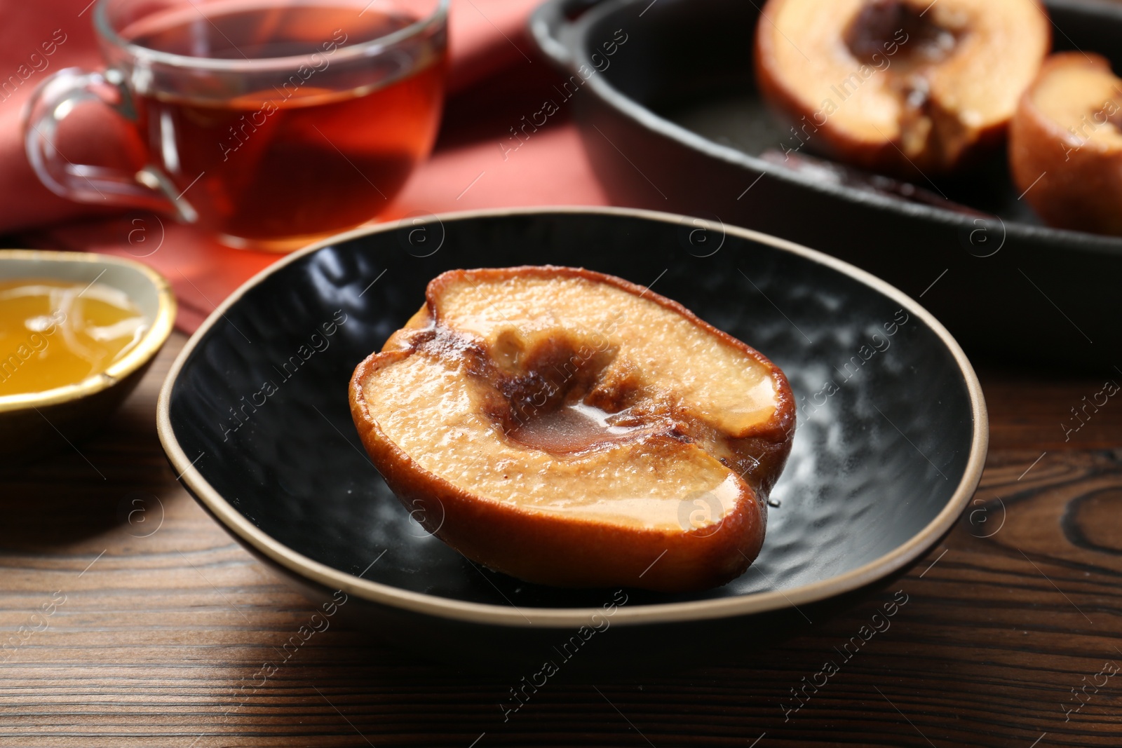 Photo of Tasty baked quince with honey in bowl on wooden table, closeup