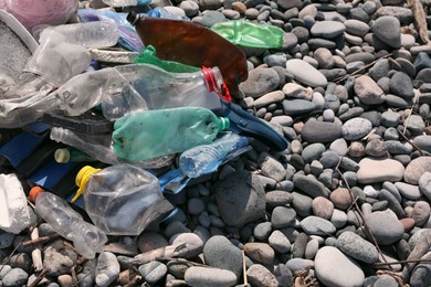 Photo of Pile of garbage on stones outdoors, closeup. Environmental Pollution concept