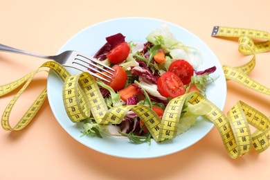 Photo of Healthy salad with measuring tape on orange background. Diet concept