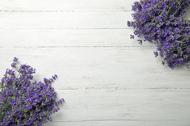 Photo of Beautiful tender lavender flowers on white wooden table, top view. Space for text