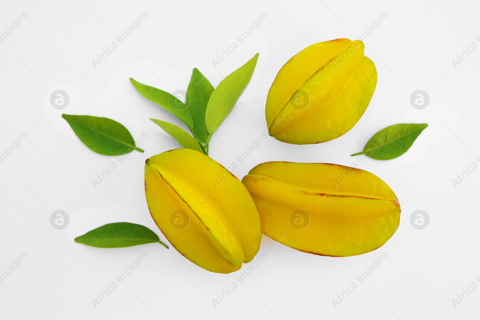 Photo of Delicious ripe carambolas with green leaves on white background