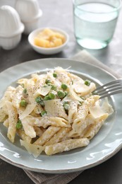 Delicious pasta with green peas, cheese and creamy sauce on grey table