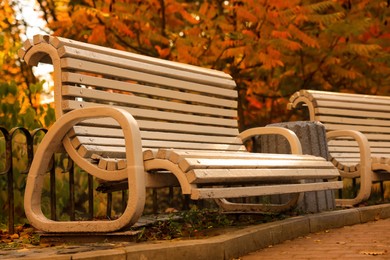 Photo of Beige wooden bench and yellowed trees in park
