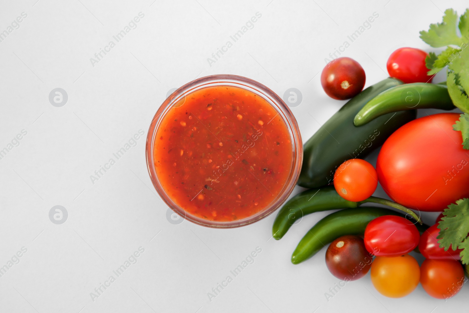 Photo of Bowl with delicious salsa sauce and ingredients on white background, flat lay. Space for text