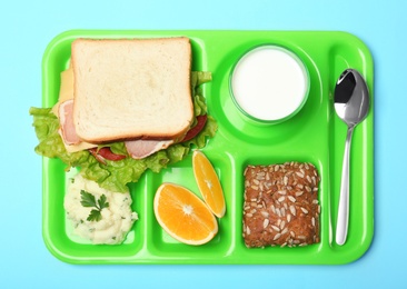 Photo of Tray with healthy food for school child on color background, top view
