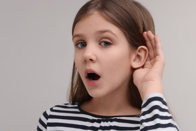 Little girl with hearing problem on grey background